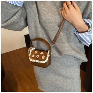Détail d'un mini sac marron avec broderie florale jaune et bordure en dentelle blanche