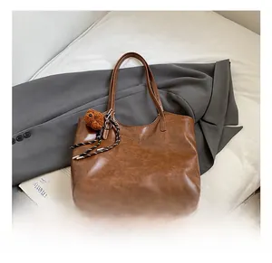 Brown leather tote bag detail with vintage texture and cute teddy bear keychain accessory