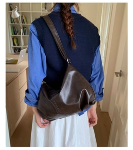 Detailed close-up of dark brown hobo bag with textured PU leather and wide shoulder strap