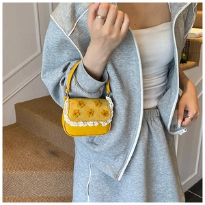 Détail du mini sac à main jaune avec fleurs en 3D et bordure en dentelle délicate