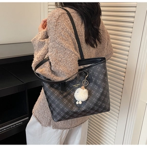 Detailed shot of large grey plaid tote bag with black strap and white plush charm accessory