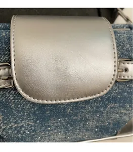 Detail of blue denim shoulder bag with silver sequins and metallic brand logo plate