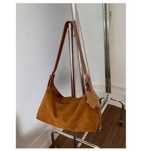 Detail of deep brown suede baguette bag with leather strap and cute plush bear charm