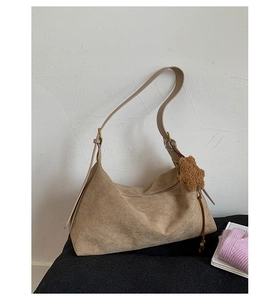 Detail view of the suede crossbody bag with star plush charm and textured fabric