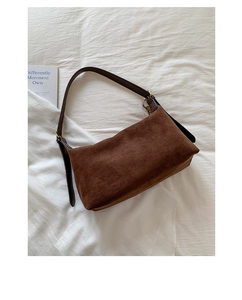 Detail view of deep brown matte suede shoulder bag with smooth leather strap and gold hardware