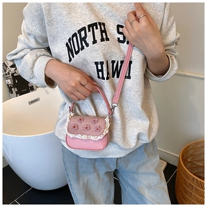 Détail du mini sac bandoulière rose avec appliques florales 3D et bordure en dentelle blanche