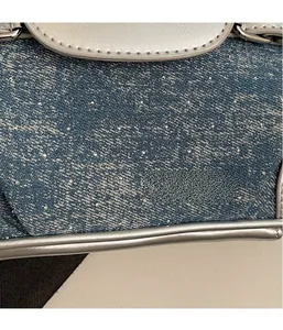Detailed close-up of blue denim fabric with sparkling rhinestones and silver leather trim