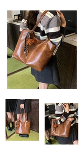 Detail view of brown leather tote bag with teddy bear charm and striped knot decoration