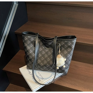 Detail of checkered tote bag with fashion lettering and cute sheep charm on wooden stairs