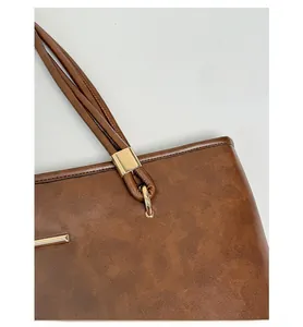 Close-up of the vintage brown leather tote bag showing gold metal buckle and strap stitching
