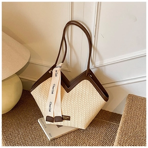 Detailed close-up of ivory woven tote bag with brown leather straps and ribbon accent