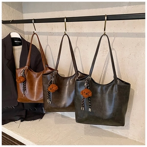 Detailed view of three vintage tote bags in caramel, coffee, and grey with teddy pendants
