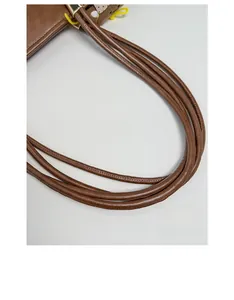 Detailed close-up of brown PU leather tote bag with round rope handle and gold metal hardware