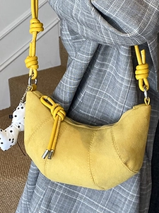 Yellow croissant crescent bag with knot strap and dog plush charm on grey blazer