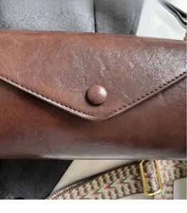 Macro shot of brown oil wax leather bag with vintage texture and colorful woven strap