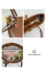 Detail of large brown PU leather tote bag showing charms and spacious interior for books