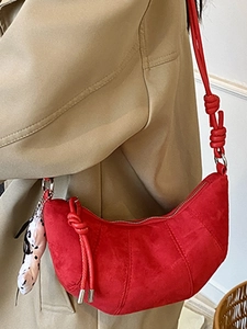 Fashionable red crescent bag in matte suede with rope strap on a khaki trench coat