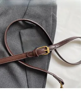 Detail of adjustable dark brown leather strap with golden buckle on suit fabric