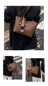 Detailed macro view of dark brown leather tote bag with rabbit charm and gold lettering