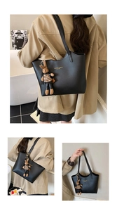 Detailed view of black leather tote bag with gold lettering and rabbit charm accessory