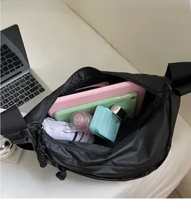 Detail view of spacious black crossbody bag interior with tablet and umbrella storage