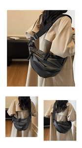 Detail of black nylon crescent bag featuring wide adjustable strap and woven rope accent