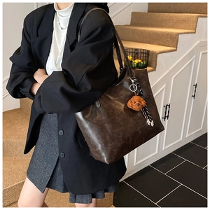 Detail of dark brown tote bag with leather texture and cute plush dog pendant accessory