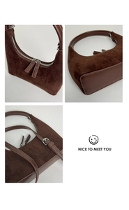 Detail view of brown suede underarm bag featuring silver zippers and smooth leather strap