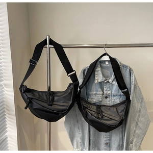 Detail of black nylon crescent crossbody bag featuring pleated fabric and adjustable strap