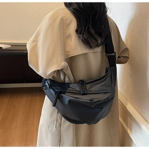 Detail showing the adjustable wide shoulder strap and woven zipper pull on black crossbody bag