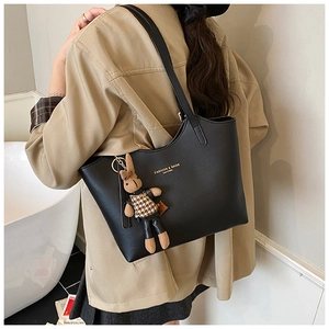 Detail of black leather tote bag featuring gold lettering and cute bunny pendant charm