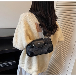 Detailed view of grey textured underarm bag with leather trim on model shoulder
