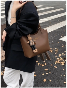 Fashionable brown leather tote bag with rabbit charm shown in a street style setting