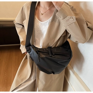 Detail of black crescent crossbody bag with woven zipper and wide nylon shoulder strap