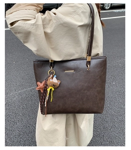 Detail of dark brown vintage tote bag with cute bear pendant and star charms
