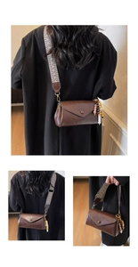 Detail of dark brown faux leather bag with patterned strap and beaded charm pendant