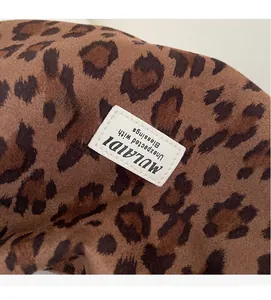 Close-up of leopard print fabric texture and stitched brand label on a large tote bag