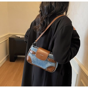 Detail of blue denim and brown leather stitching on a stylish shoulder bag for women