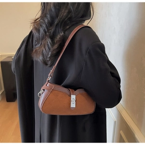 Close-up of brown quilted saddle bag with matte leather finish and silver metal lock