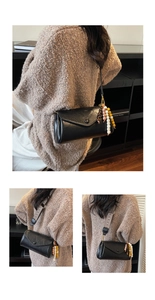 Detail of black faux leather crossbody bag with wooden bead tassels and wide strap