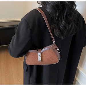 Close-up of brown suede shoulder bag with diamond stitching and silver metal buckle