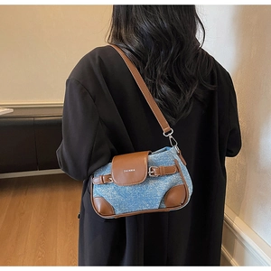 Detail of a denim shoulder bag with brown leather trim and white ZHCNMA logo