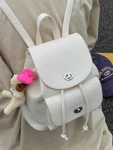 Vintage beige textured leather backpack with plush dog charm and metal clasp for outdoor travel