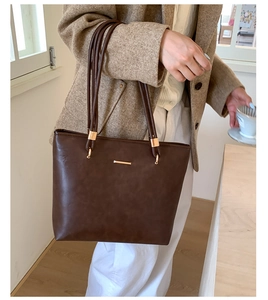 Close-up of matte dark brown PU leather tote with gold buckle and metallic detail