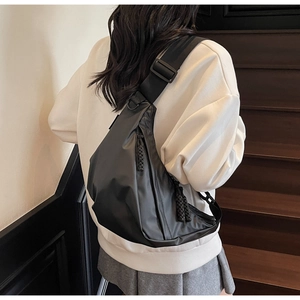 Detail of water-resistant black nylon crossbody bag featuring adjustable woven strap and zippers