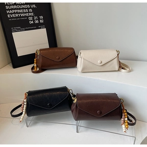 Detailed close-up of retro envelope crossbody bags with wooden beaded chain accessory