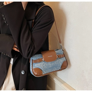 Detail view of retro denim baguette bag with brown leather trim and ZHCNMA logo