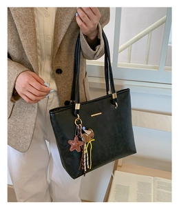 Close-up of black PU leather tote bag with star and bear charms for office commute
