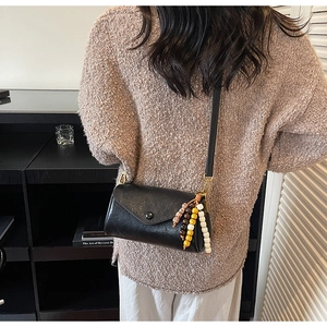 Chic black leather crossbody bag with colorful wooden beads shown on a model