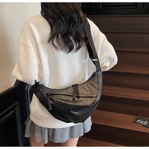 Back view of a model wearing a black nylon crescent crossbody bag on modern stairs